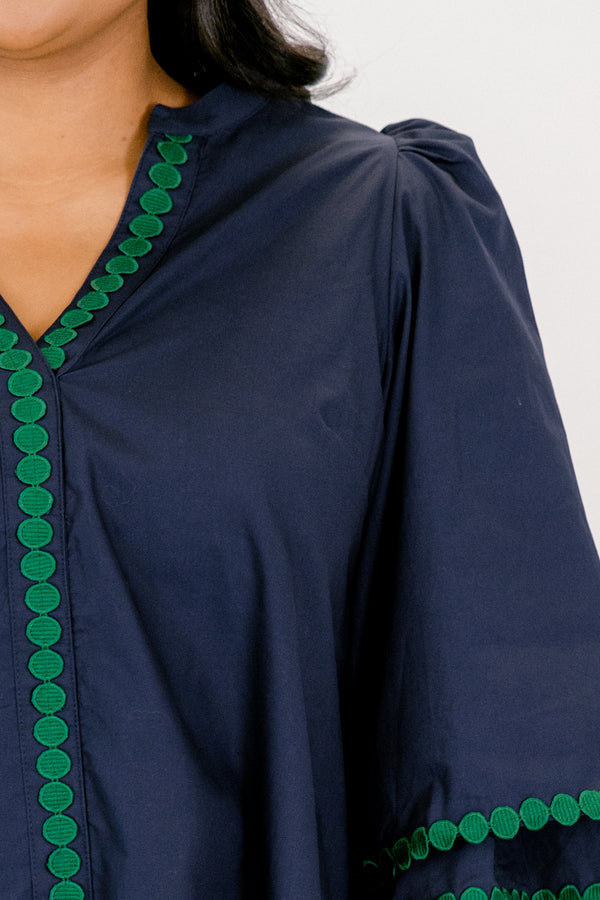 Chic Soul plus size clothing, Navy top with half bell sleeves, v-neckline, along with green polka dot details on the sleeves, neckline, and going down the center of the shirt 