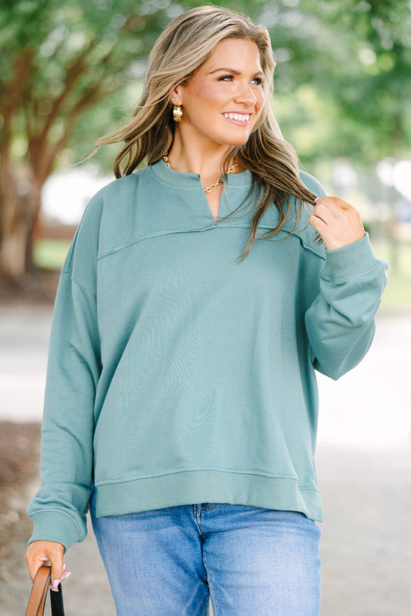 Plus size green tunic sweatshirt with a split v-neck, raw seam details, and a relaxed fit.