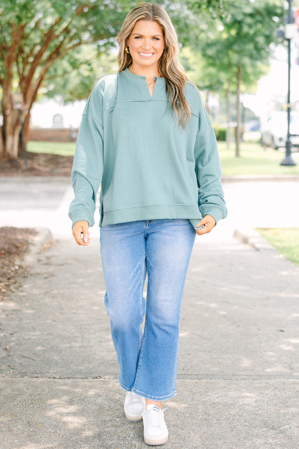 Plus size green tunic sweatshirt with a split v-neck, raw seam details, and a relaxed fit.