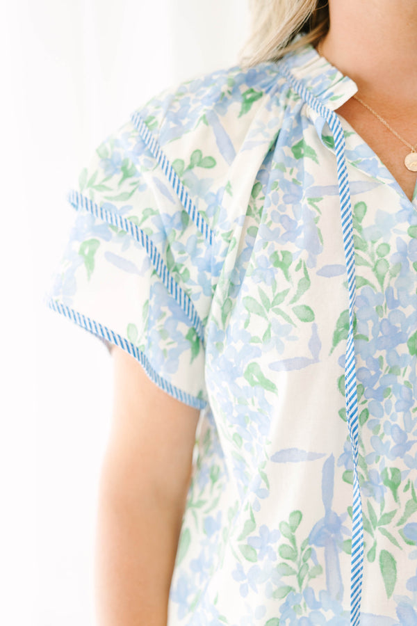 Plus size blue floral ruffle sleeve top with v neckline that ties with tassels across the neck