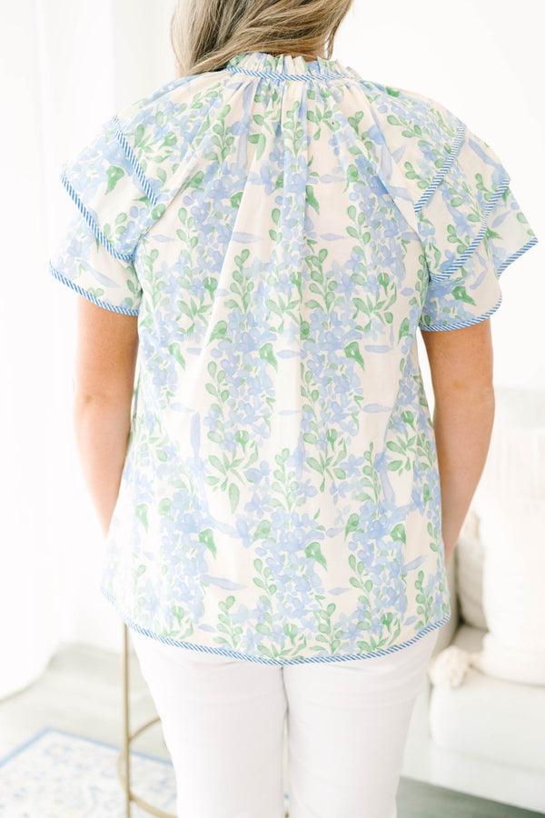 Plus size blue floral ruffle sleeve top with v neckline that ties with tassels across the neck