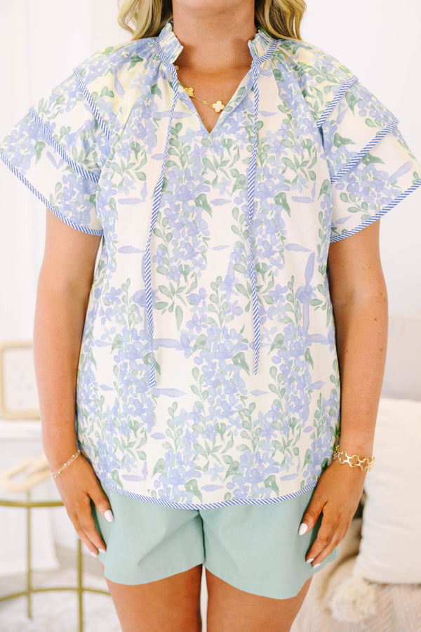 Plus size blue floral ruffle sleeve top with v neckline that ties with tassels across the neck