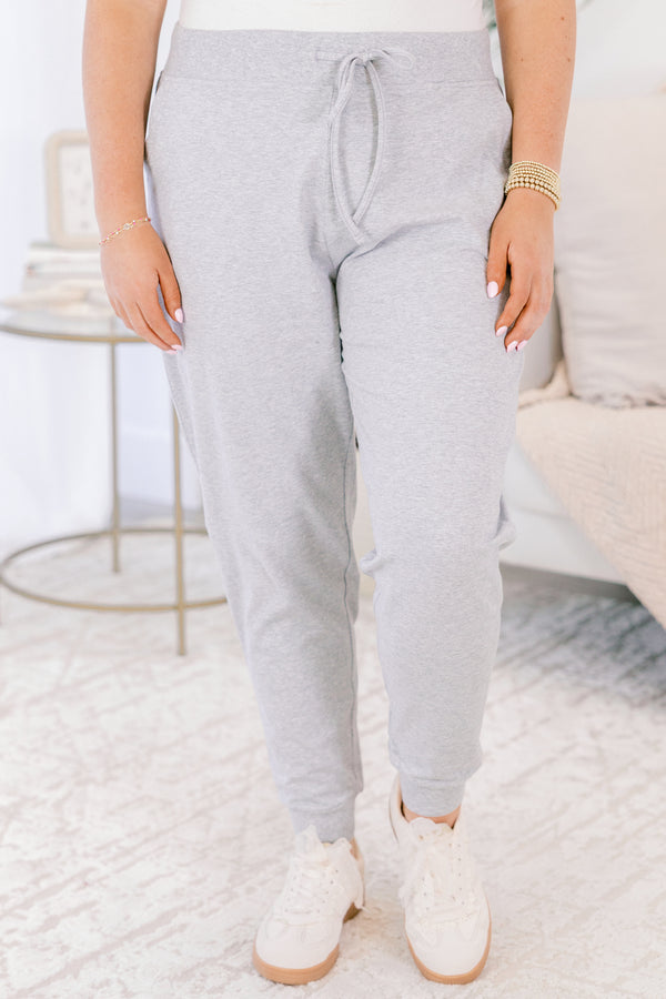 Person wearing gray sweatpants and white shoes in a minimalistic room.