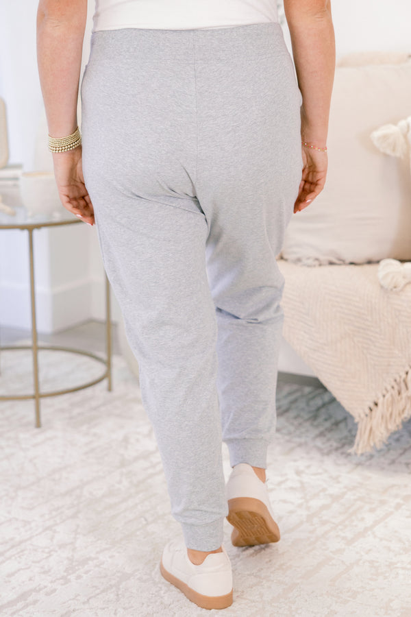 Person wearing light gray sweatpants in a cozy living room setting