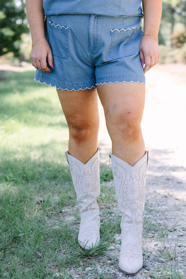 Plus Size denim shorts with white scalloped trim on the pockets and hem, paired with white boots.