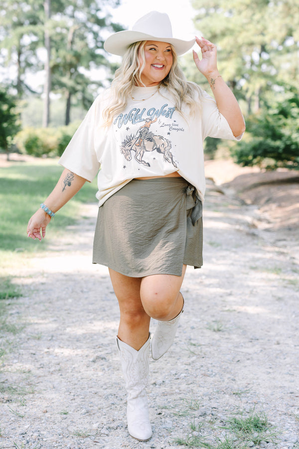 Plus Size olive green wrap-style skort with a side tie, paired with white embroidered cowboy boots.
