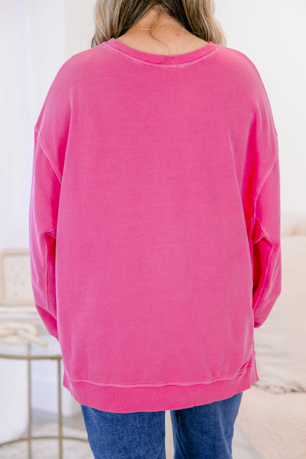 Person wearing a bright pink sweatshirt with a blurred background