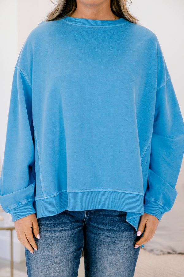Person wearing a blue sweatshirt and jeans against a white background
