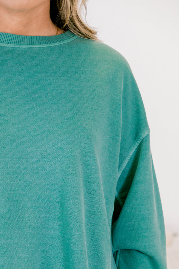 Teal sweater worn by a person on a light background