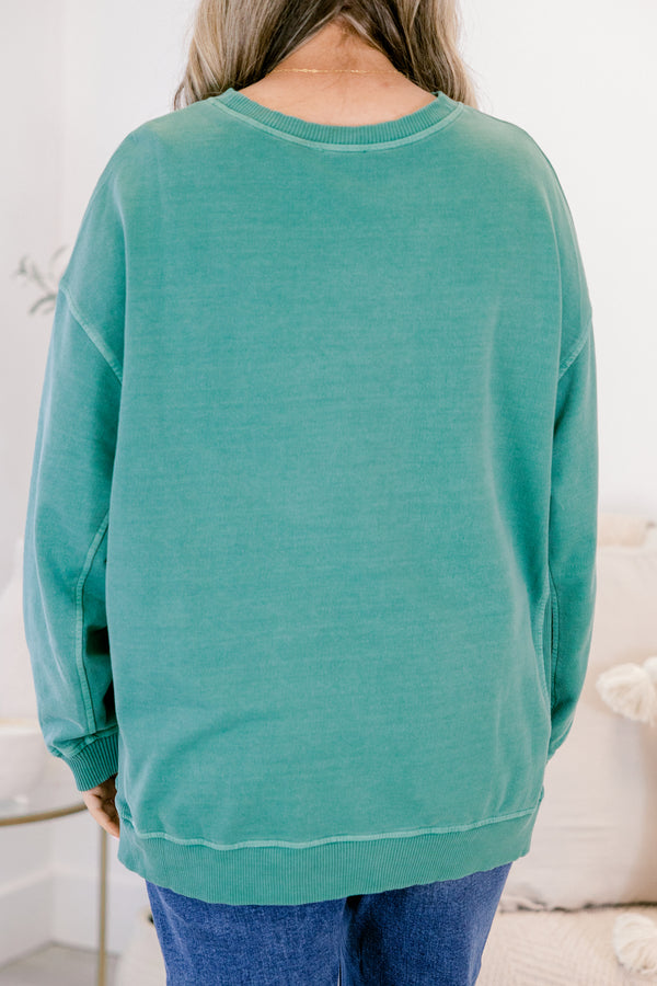 Person wearing a teal sweatshirt in a casual setting