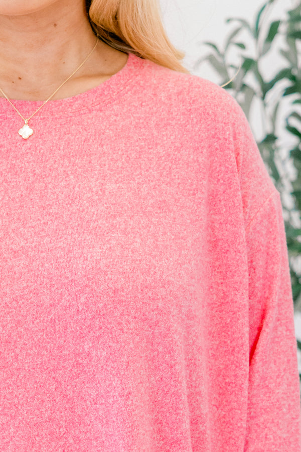 Close-up of a person wearing a pink sweater with a blurred background