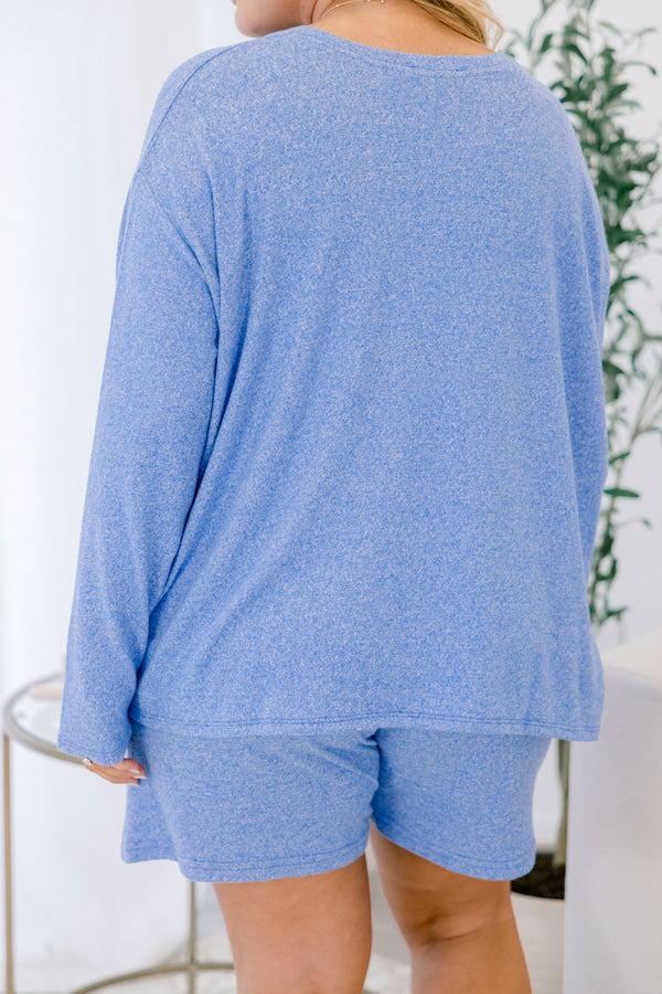 Person wearing a blue long-sleeve top and shorts set with a white background