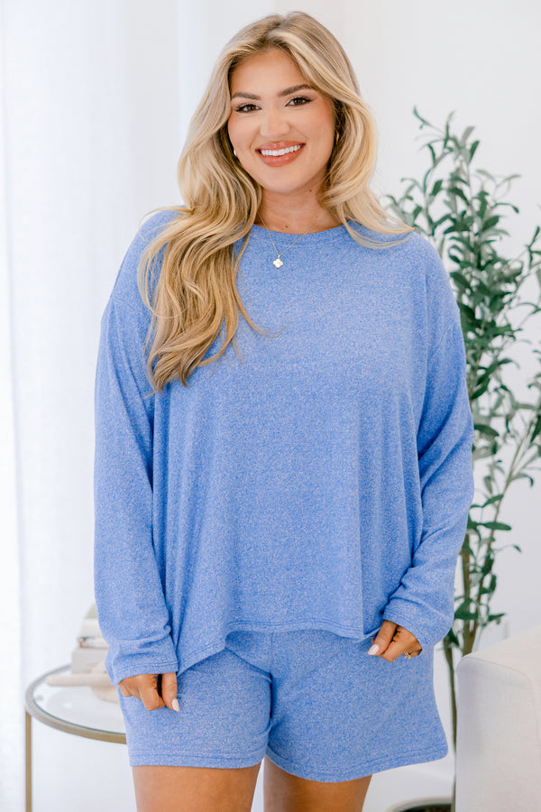 Woman wearing a blue outfit with a plant in the background