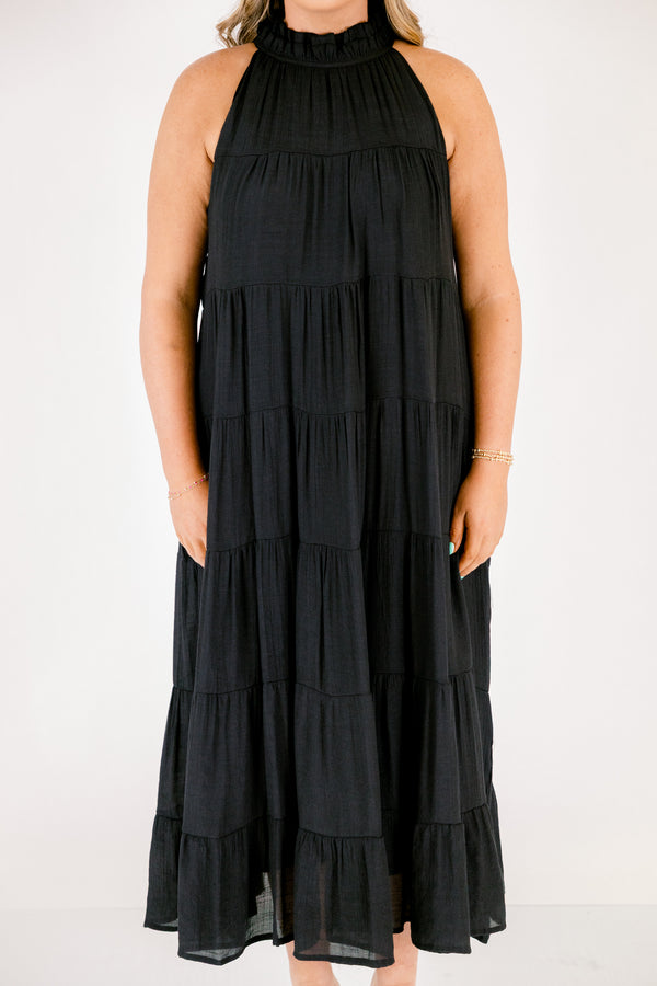 Chic Soul plus size clothing, tiered black maxi dress with a high neck that has ruffle detailing on the neckline and a bow that ties on the back of the neck at the top 