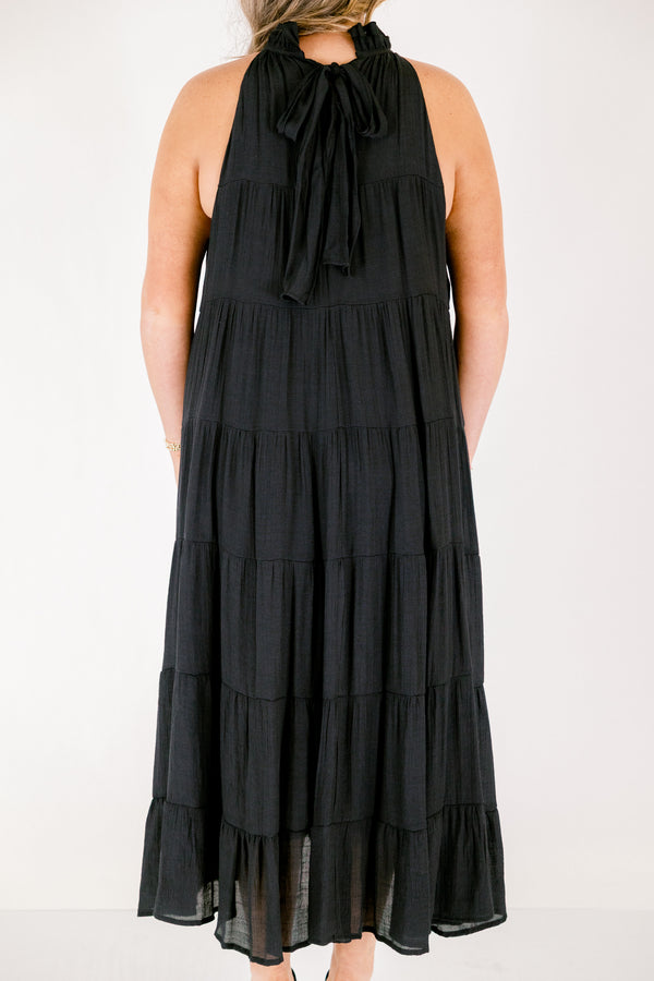 Chic Soul plus size clothing, tiered black maxi dress with a high neck that has ruffle detailing on the neckline and a bow that ties on the back of the neck at the top 