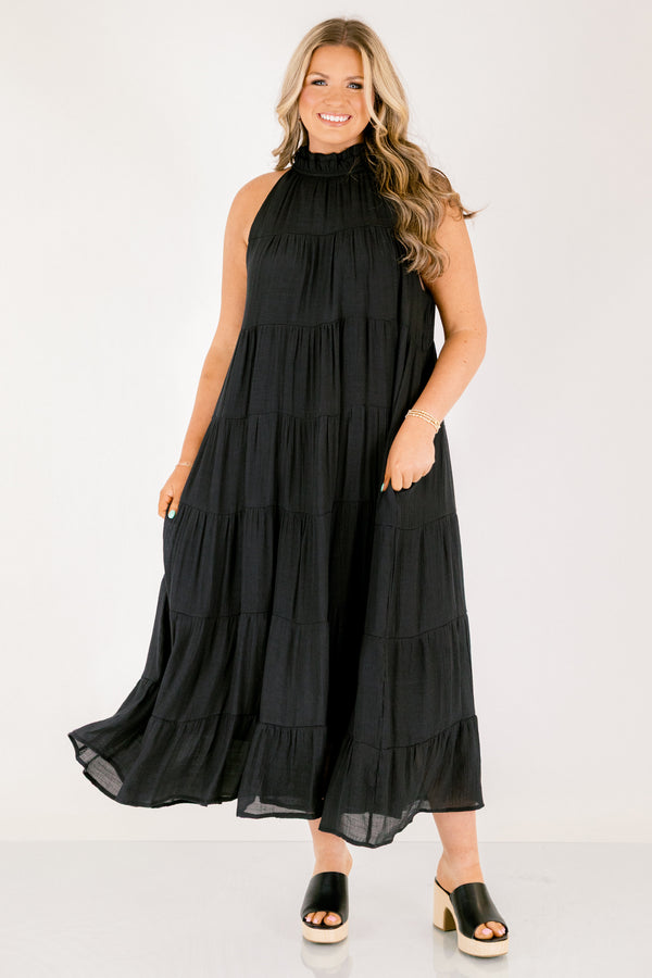 Chic Soul plus size clothing, tiered black maxi dress with a high neck that has ruffle detailing on the neckline and a bow that ties on the back of the neck at the top 