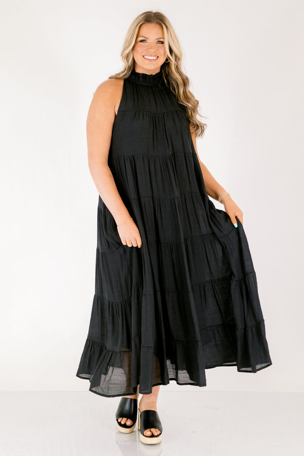 Chic Soul plus size clothing, tiered black maxi dress with a high neck that has ruffle detailing on the neckline and a bow that ties on the back of the neck at the top 