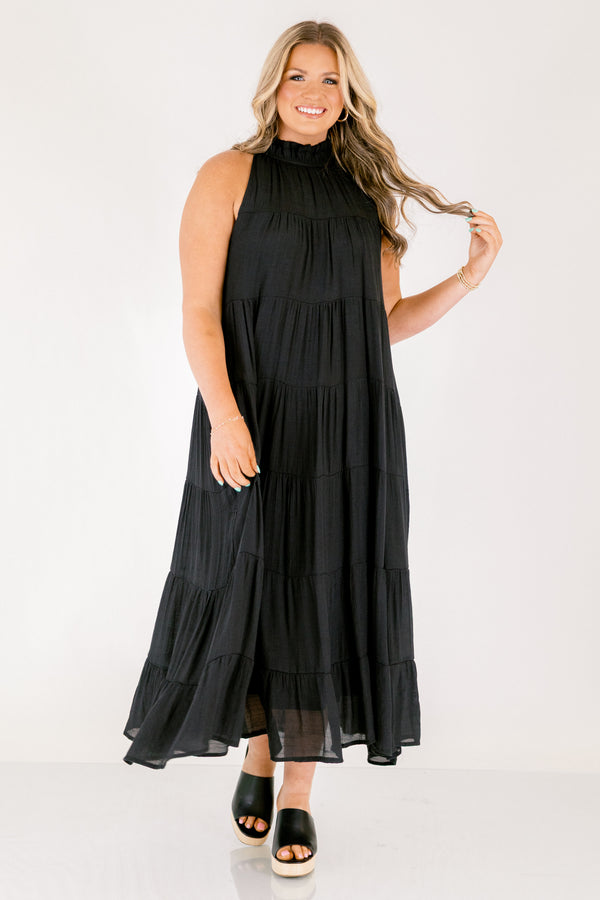 Chic Soul plus size clothing, tiered black maxi dress with a high neck that has ruffle detailing on the neckline and a bow that ties on the back of the neck at the top 