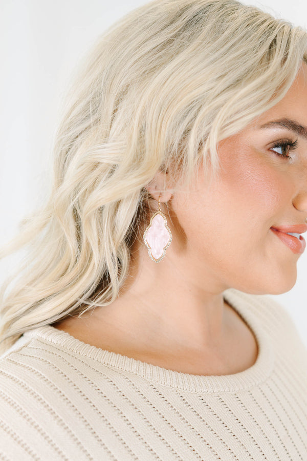 Earrings with pink stone inlays and etched gold metal frames.
