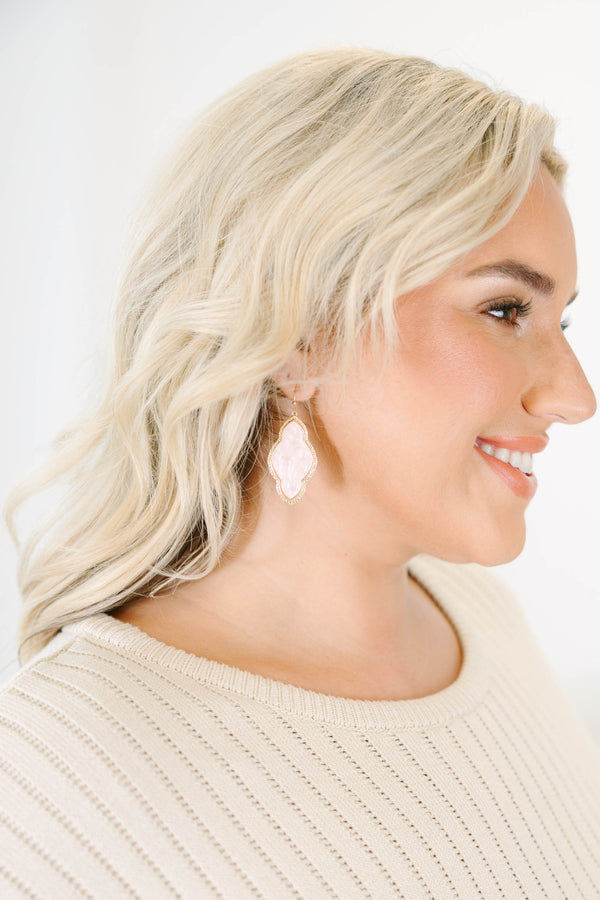Earrings with pink stone inlays and etched gold metal frames.