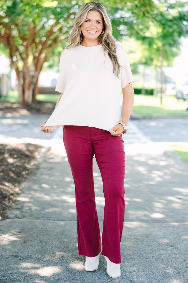 Plus size dark rose flare jeans with a high-waisted fit and stretchy fabric.