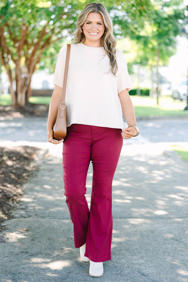 Plus size dark rose flare jeans with a high-waisted fit and stretchy fabric.