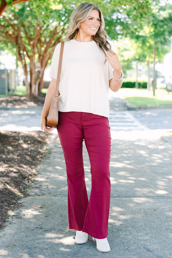 Plus size dark rose flare jeans with a high-waisted fit and stretchy fabric.