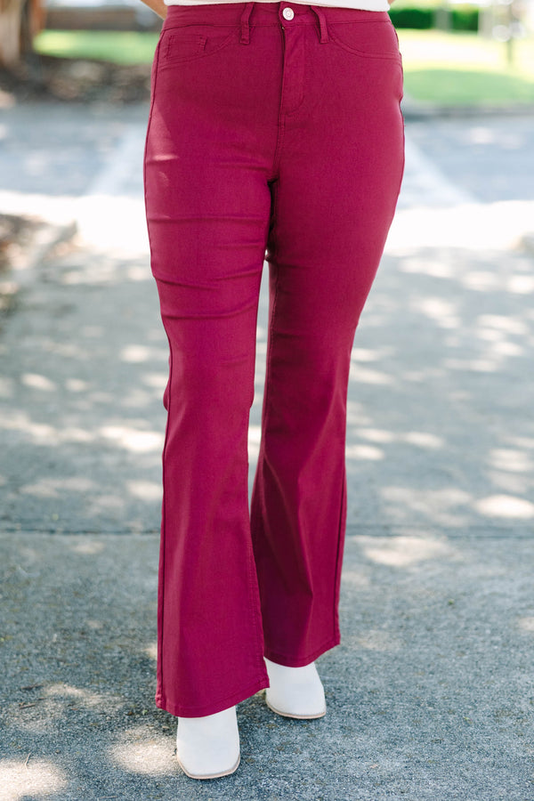 Plus size dark rose flare jeans with a high-waisted fit and stretchy fabric.