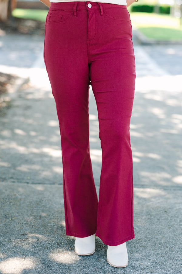 Plus size dark rose flare jeans with a high-waisted fit and stretchy fabric.