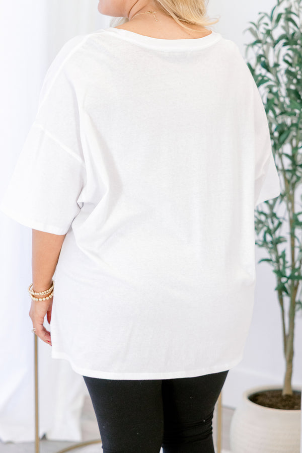 Person wearing a white long-sleeve top with a plant in the background