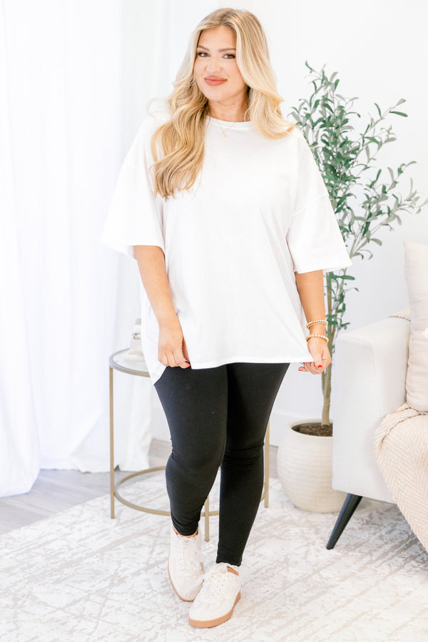 Woman wearing a white top and black leggings in a home setting