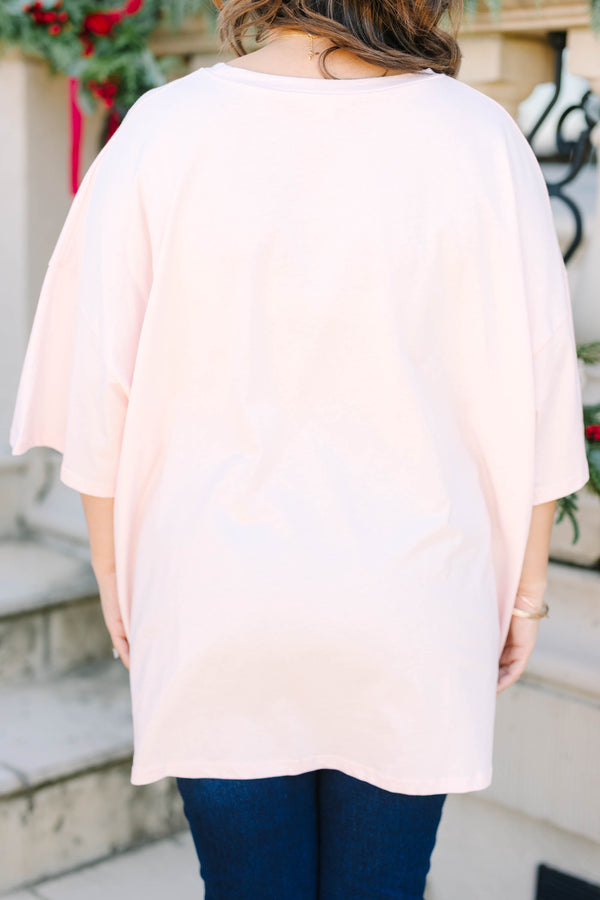 Plus size woman in a flowy cream pink boyfriend tee with a colorful 'MERRY' graphic and bows.