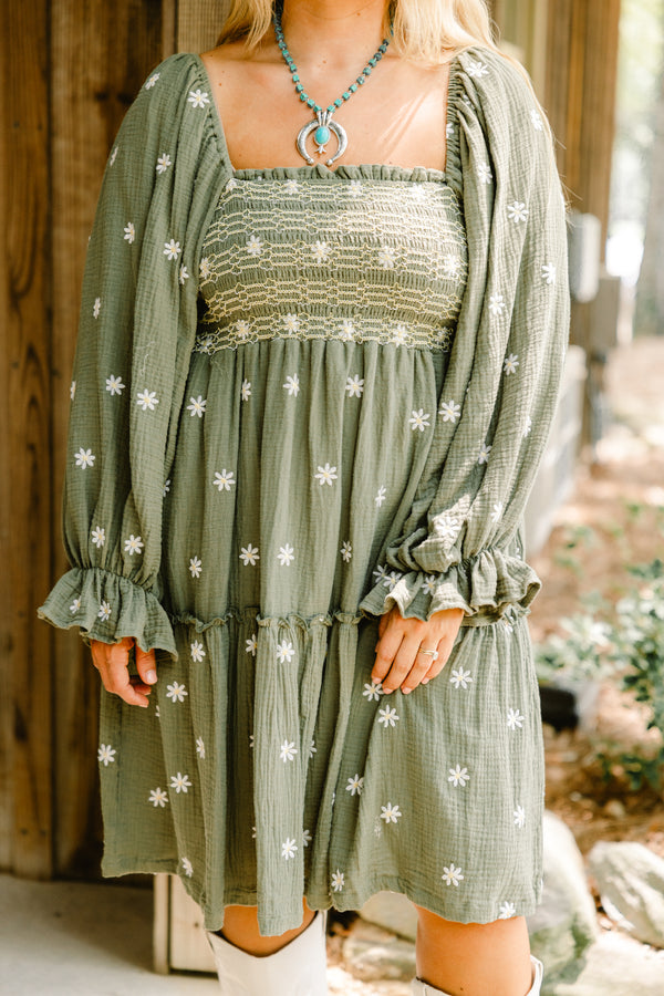 Chic Soul plus size clothing, olive baby doll dress with long sleeves that have a ruffle detail at each end of the sleeve as well as a white floral pattern throughout and stitching detail on the bust 