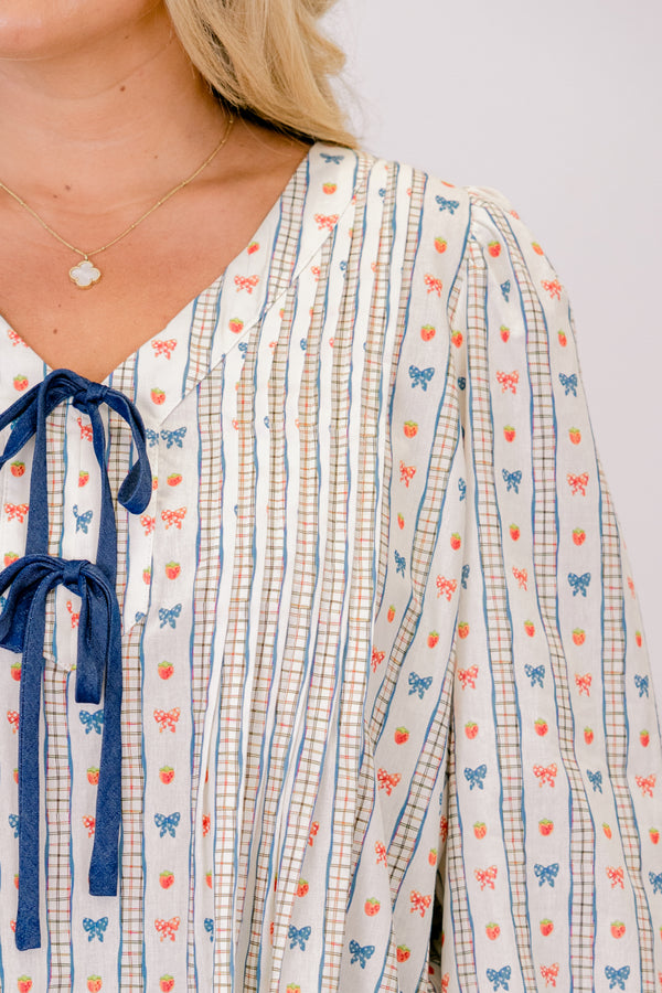 Chic Soul plus size clothing, white long sleeve top with a bow pattern and two bows going down the chest as well as ruffle details at the end of each sleeve 