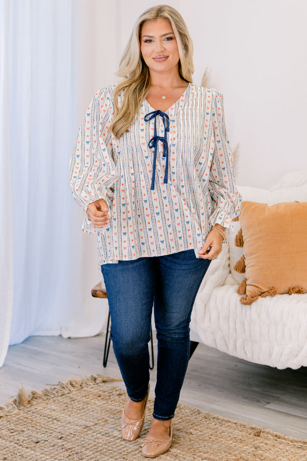 Chic Soul plus size clothing, white long sleeve top with a bow pattern and two bows going down the chest as well as ruffle details at the end of each sleeve 