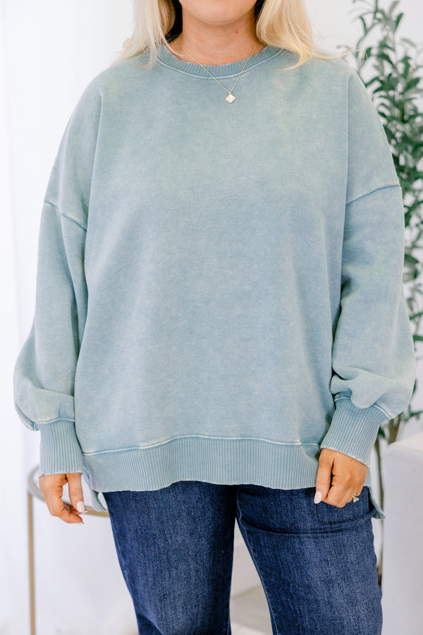 Person wearing a light blue sweatshirt and dark jeans against a white background
