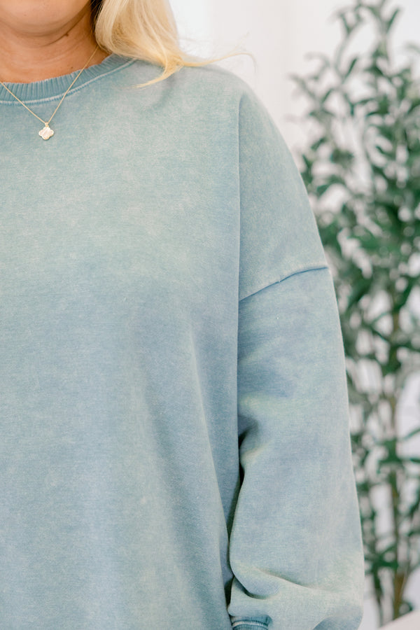 Light blue sweatshirt worn by a person with a blurred natural background