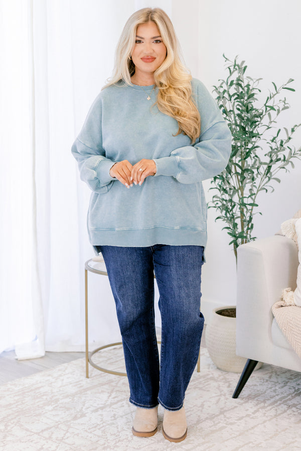 Woman wearing a light blue sweatshirt and jeans in a home setting
