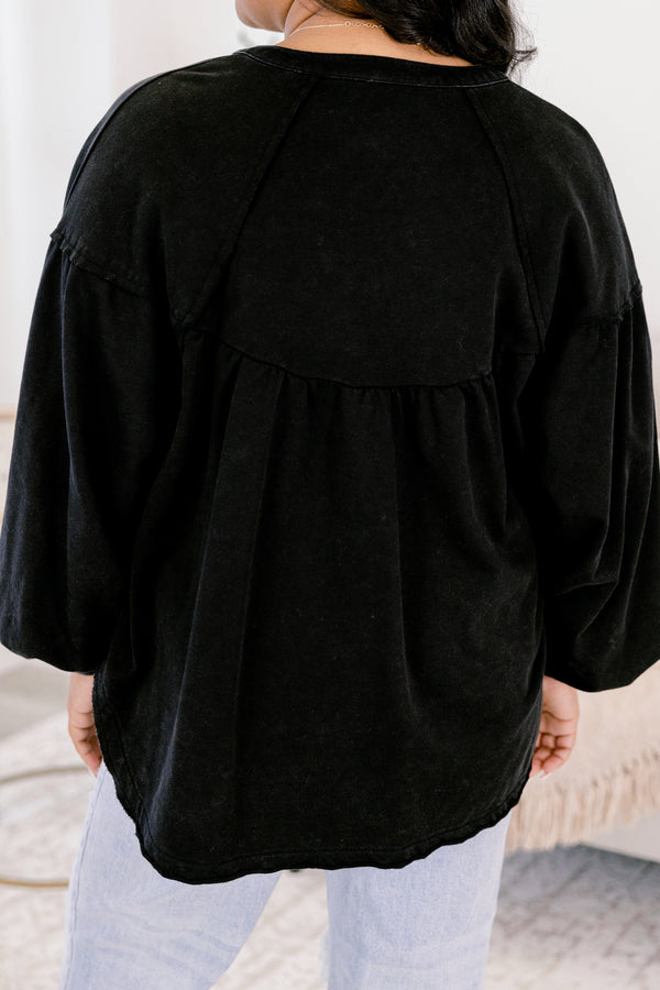 Person wearing a black oversized shirt with light blue pants in a neutral setting