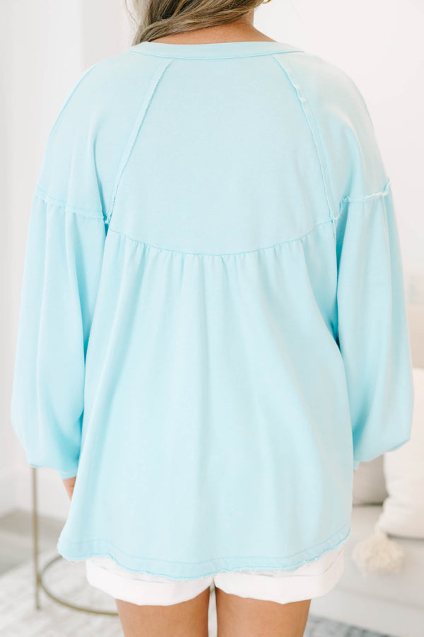 Plus size light blue pullover with a flowy fit, button-up neckline, and long sleeves.