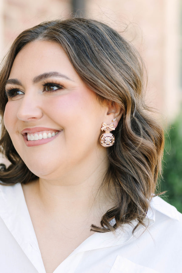 Gold crystal snowflake ornament earrings with a bow detail.