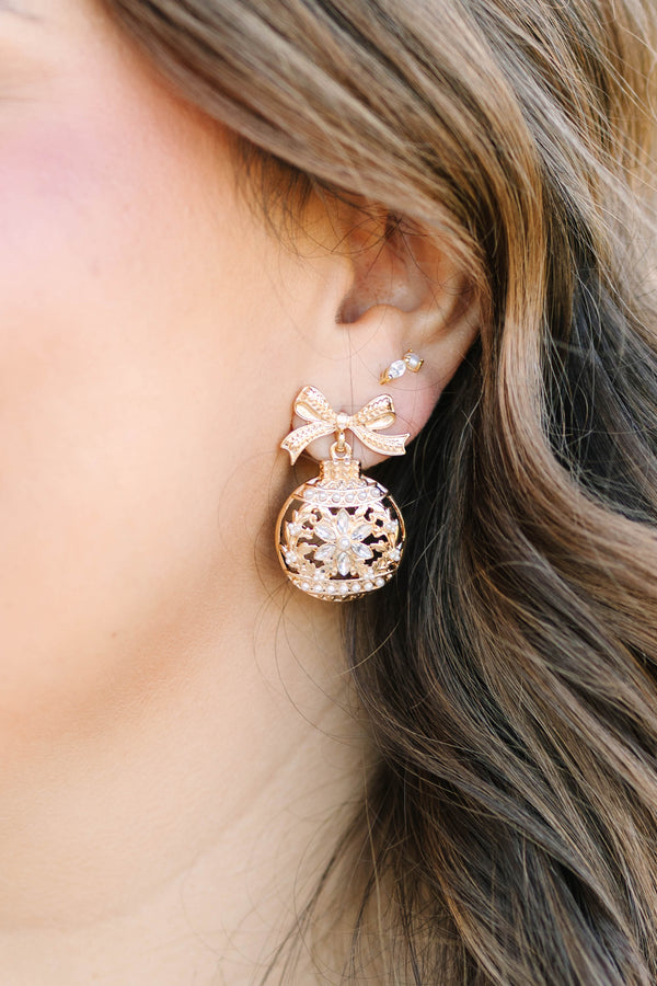 Gold crystal snowflake ornament earrings with a bow detail.
