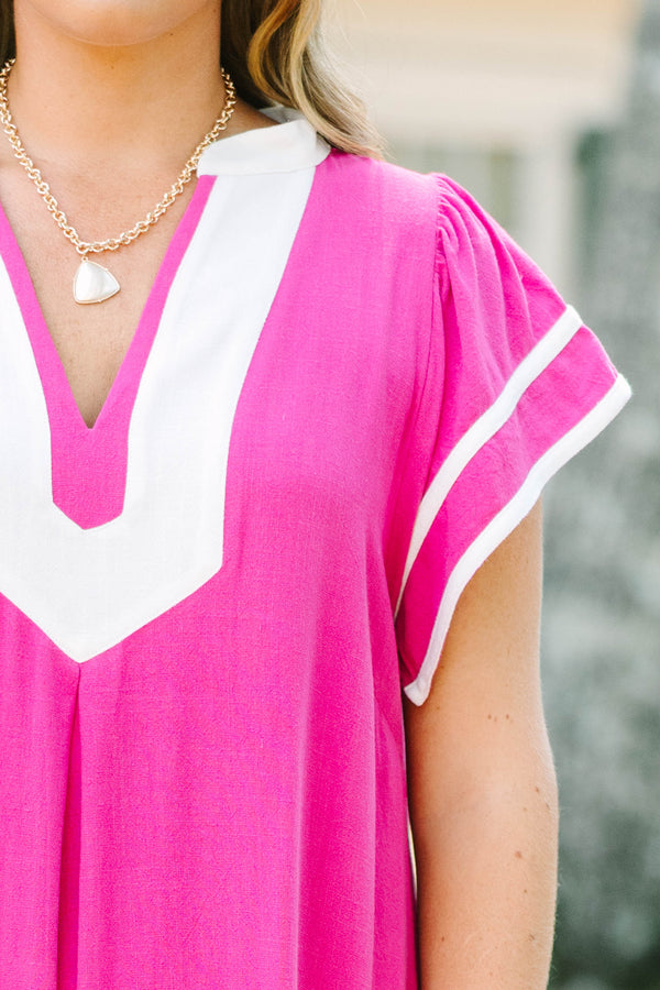 Plus size pink maxi dress with white trim, V-neckline, and flowy short sleeves.