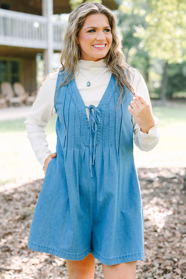 Plus Size denim romper with a tie-front V-neckline and pleated details over a white turtleneck.