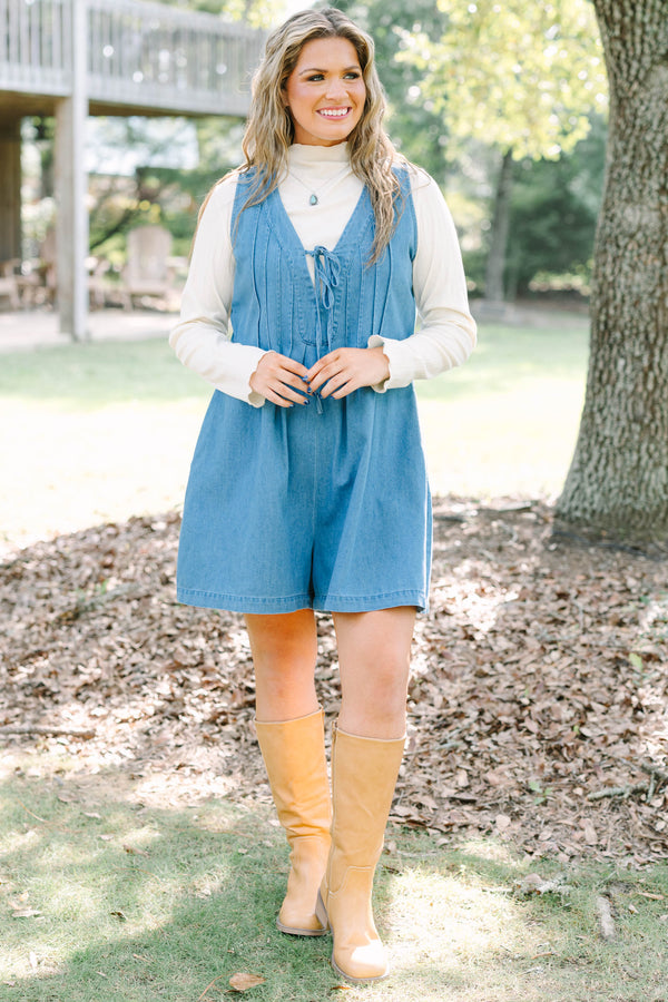 Plus Size denim romper with a tie-front V-neckline and pleated details over a white turtleneck.