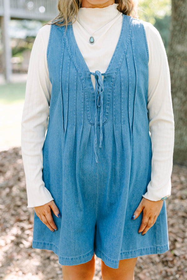 Plus Size denim romper with a tie-front V-neckline and pleated details over a white turtleneck.