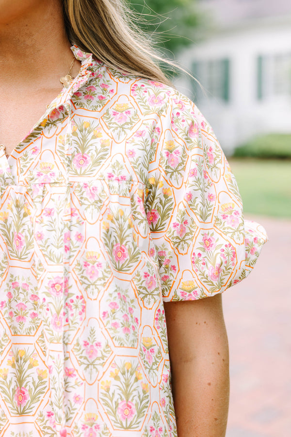 Plus Size pink floral print top with puff sleeves, a ruffled neckline, and tassel details.