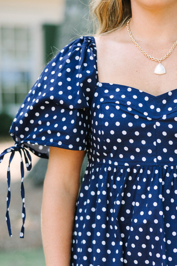 Plus Size navy blue polka dot cotton dress with puff sleeves, tie details, and a tiered skirt.