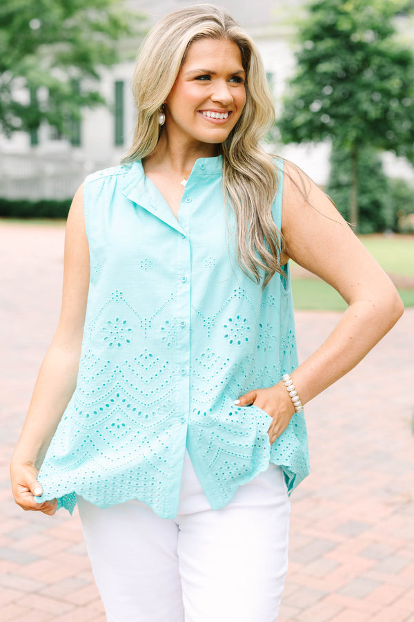 Plus Size turquoise sleeveless eyelet button-down top with a scalloped hem and white pants.