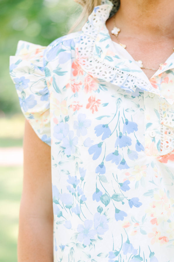 Plus Size white floral top with ruffle cap sleeves, a lace-trimmed collar, and white pants.